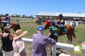 Keen horse enthusiasts gathered at the mounting yard to watch jockeys prepare for the races.