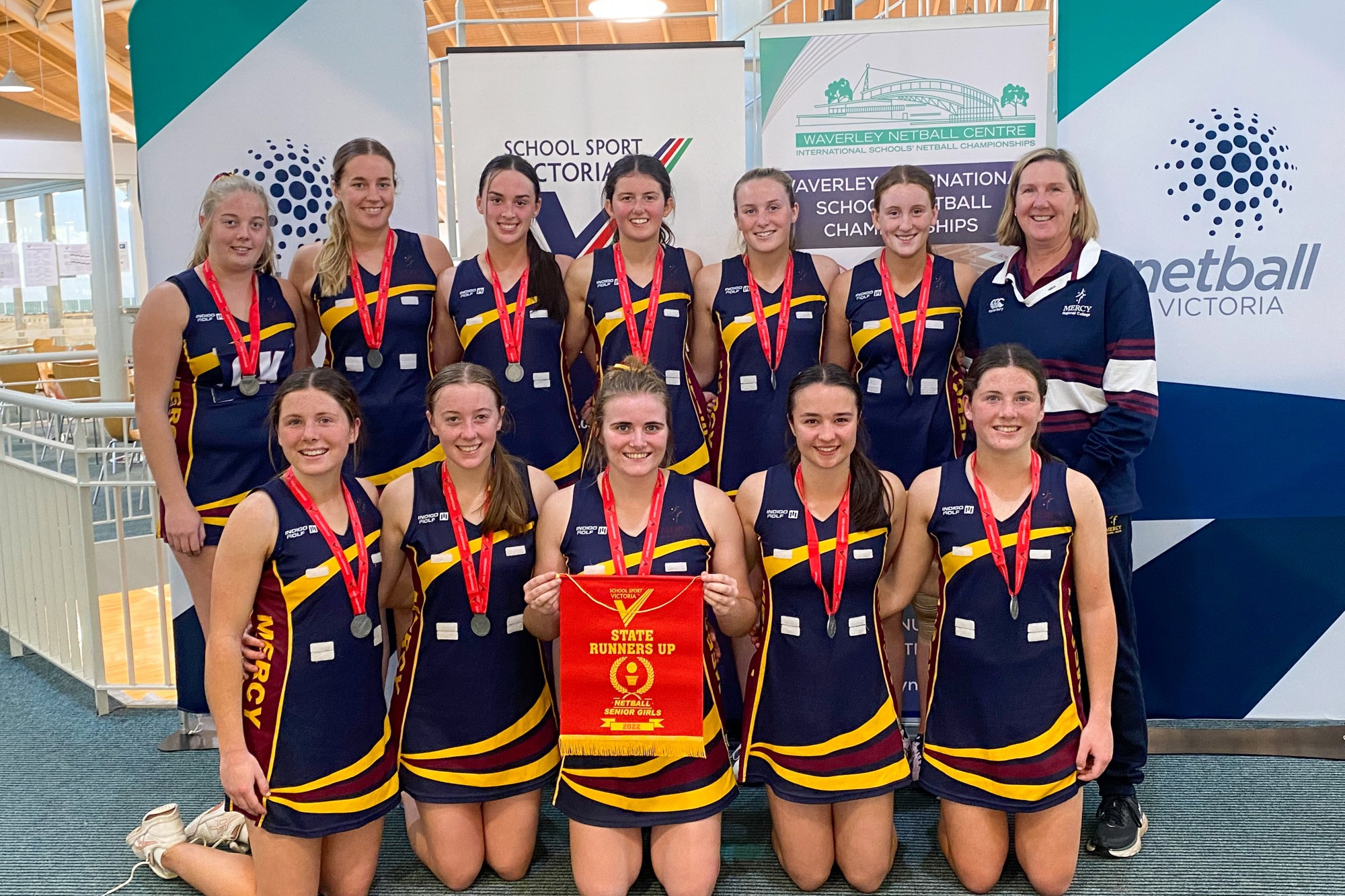 MRC netballers celebrate their grand final appearance. Top right, from left: Holly, Georgia, Ruby, Jessica, Ava, Isabelle and coach Sharon Gillett. Front: Lara, Mary, Ella, Emily and Grace.