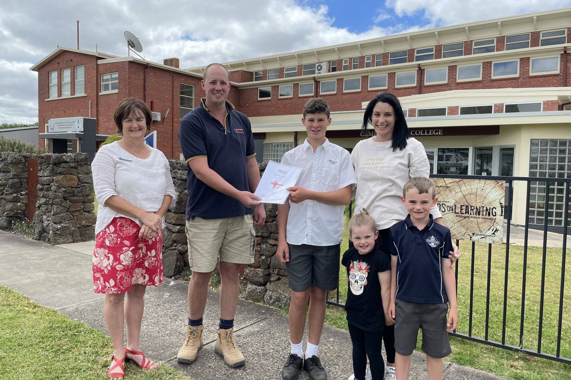 Congratulations: Camperdown College principal Cherie Kilpatrick and school council member Luke Webb congratulate the Messer family on winning a $10,000 travel voucher in the school raffle.