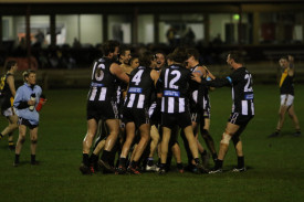 Get around him: The Pies swarm Baker after booting his first senior goal. 