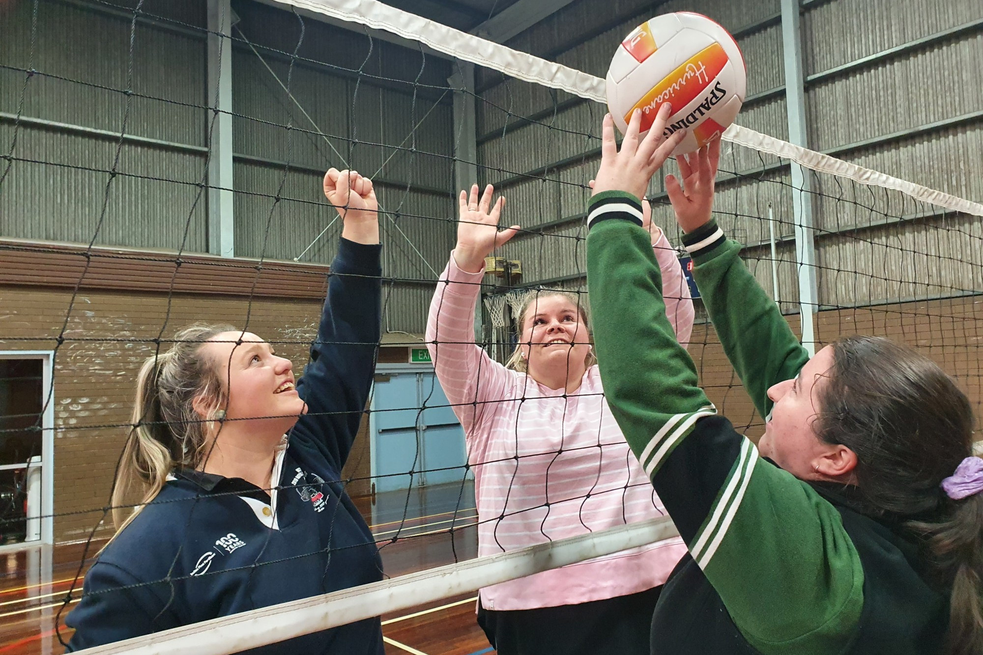 Opposing players enjoy the warm up together with Tiffany McLauchlan (left) and Hayley Hart reaching for the heights while Ingrid Bellman controls the ball on the near side.