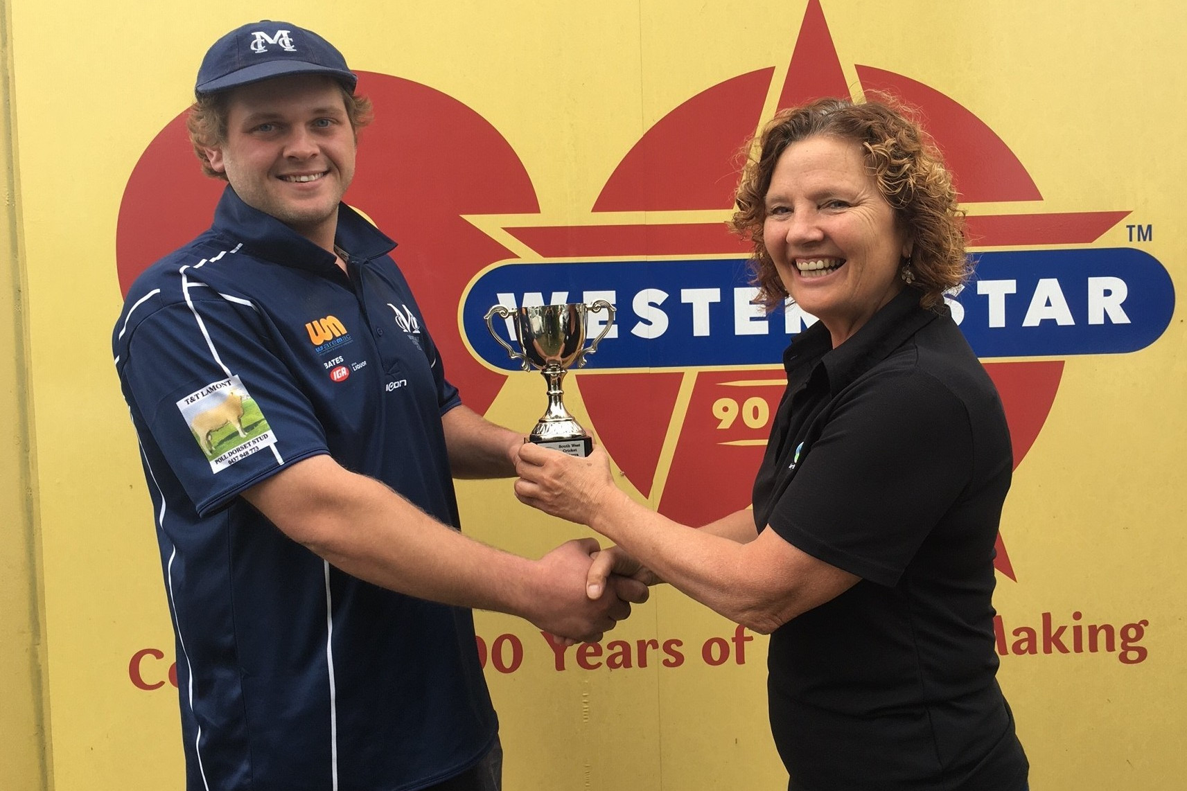 Cats’ captain Tyler Schafer accepts the trophy from Fonterra farm source area manager Jocelyn Bevin.