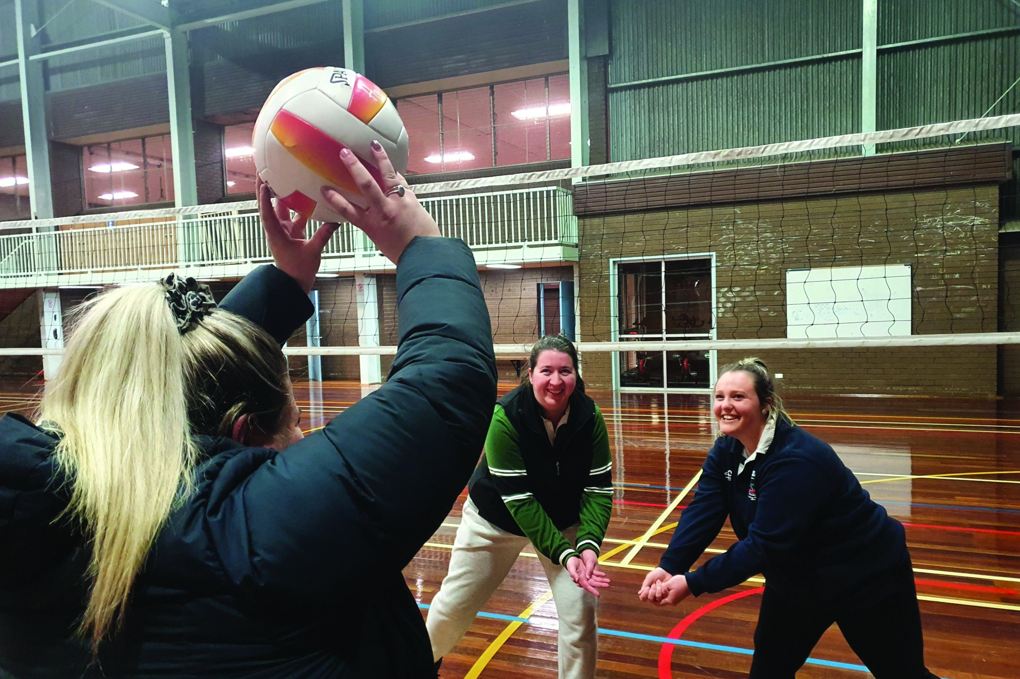 Opposing players enjoy the warm-up together with Hayley Hart (nearest camera) setting the ball to Ingrid Bellman (left) and Tiffany McLauchlan.