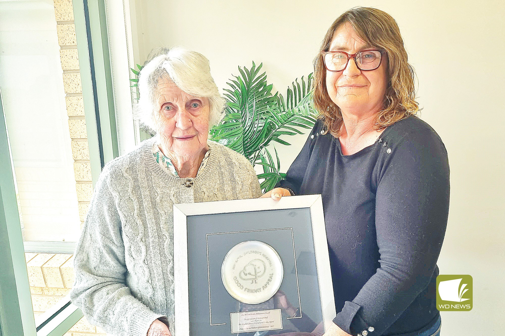 An honour: Timboon Good Friday Appeal area manager Lee Edge (right) show’s Les Gunn’s (deceased) wife Gwenda a plaque commemorating $1 million in funds raised for the appeal..