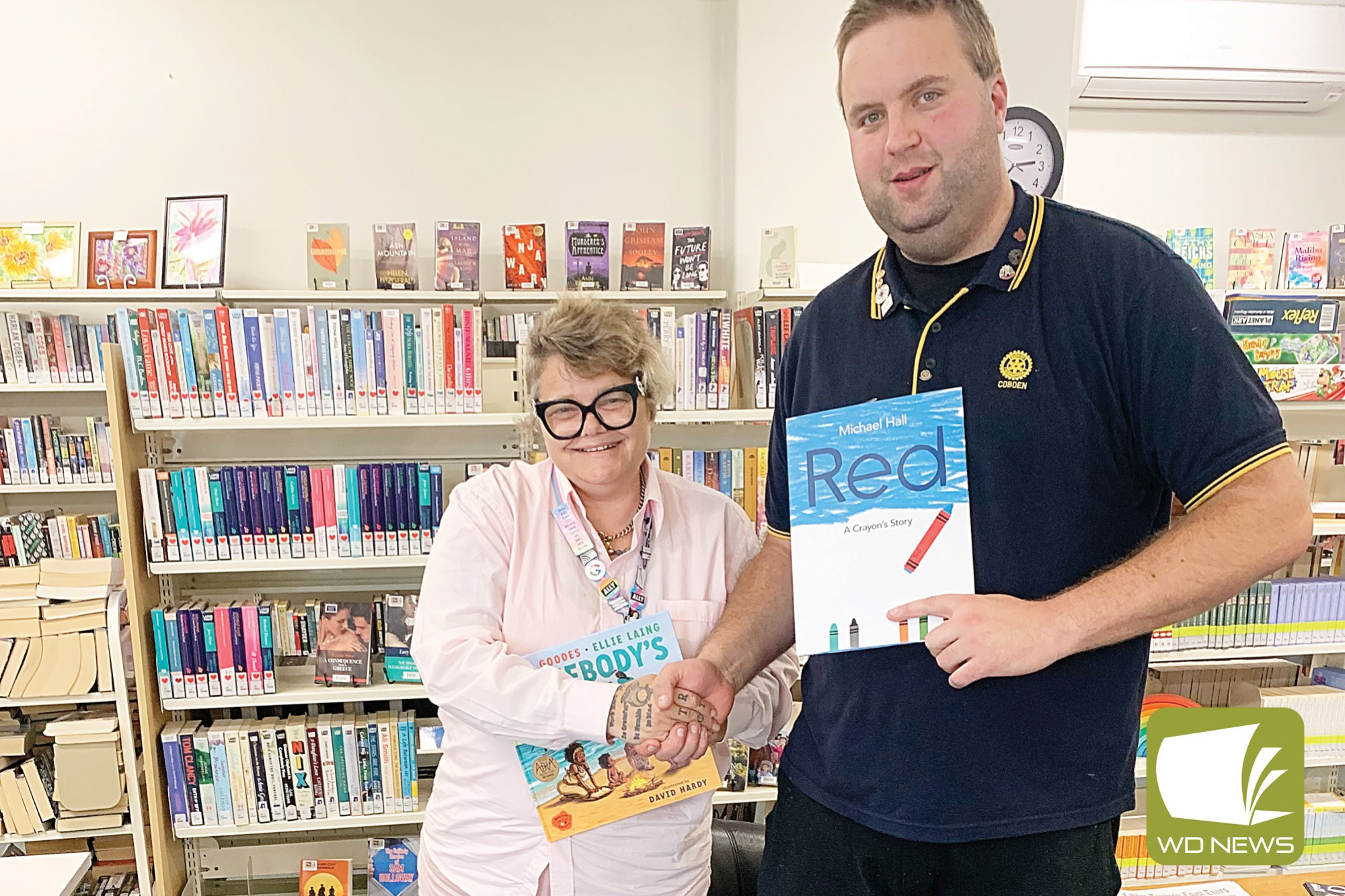 Rotary Club president David Childs presents Cobden librarian Faith Chapman with 10 new books for the library.