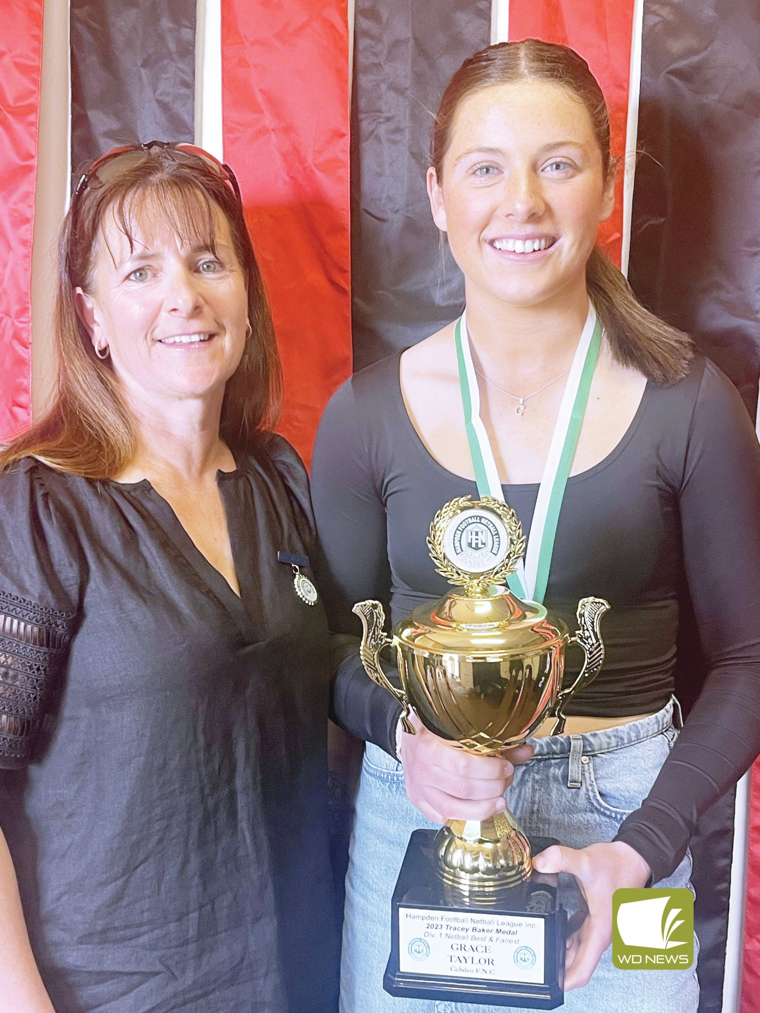 Cobden’s Grace Taylor is presented with her division one best and fairest award by Tracey Baker.