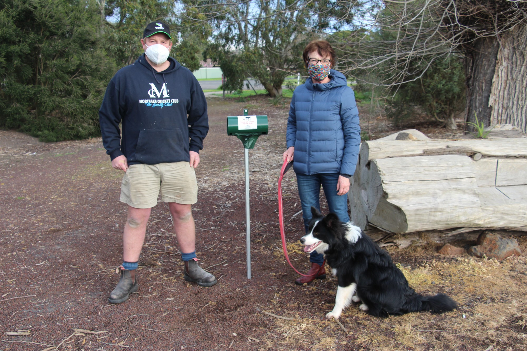 Installed: Mortlake Recreation Reserve Committee of Management members Todd Robertson (left) and Dianne Murphy, with her border collie Ray, show off the newly installed dog tidy bag dispensers which have made the reserve more dog efficient.