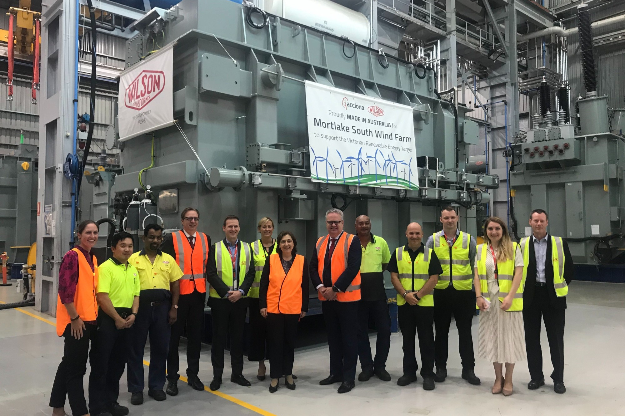 Next step: Minister for Energy, Environment and Climate Change Lily D’Ambrosio (centre) ACCIONA Energy managing director Brett Wickham (sixth from right) and Wilson Transformers and ACCIONA Energy representatives celebrate the start of the journey of a $2 million transformer to the Mortlake South Wind Farm project last week.