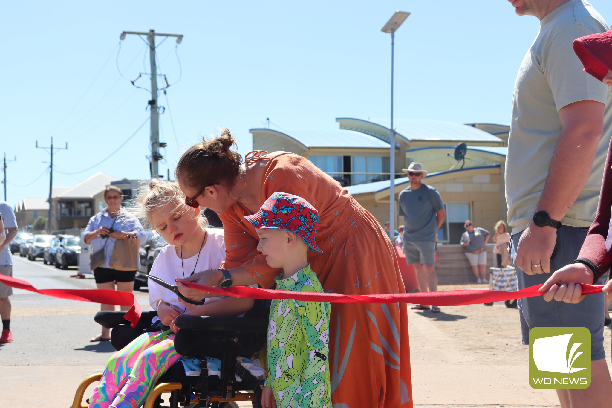 Unveiling accessibility: Goldie Elsum (left) hosts the ribbon cutting ceremony with mum Charlene Elsum and brother Rocky Elsum for beach matting named in her honour.