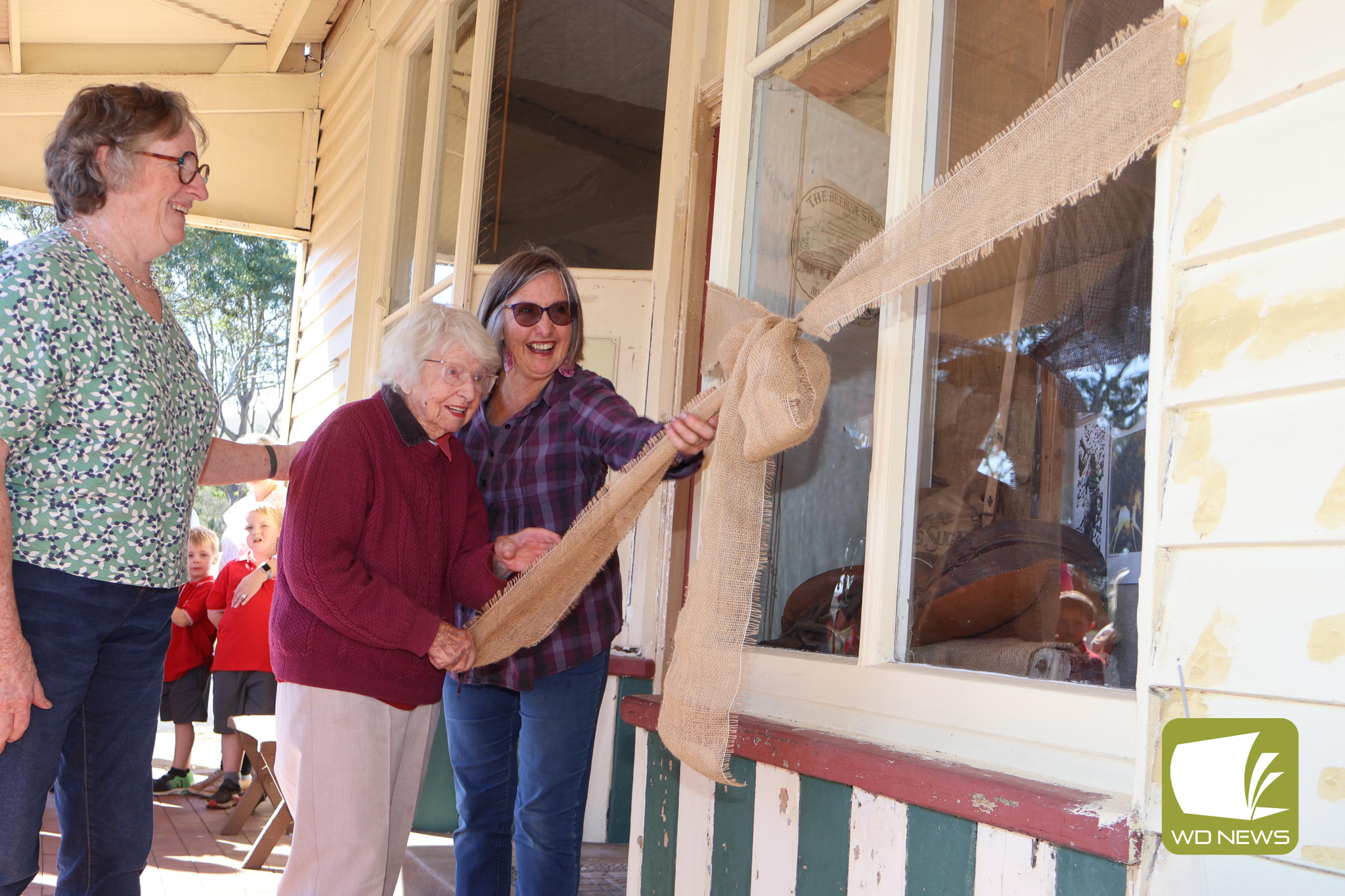 Celebration: Pam Knight, Noorat’s oldest resident, pulled down the ribbon to unveil a new shopfront display celebrating Alan Marshall on his 123rd birthday.