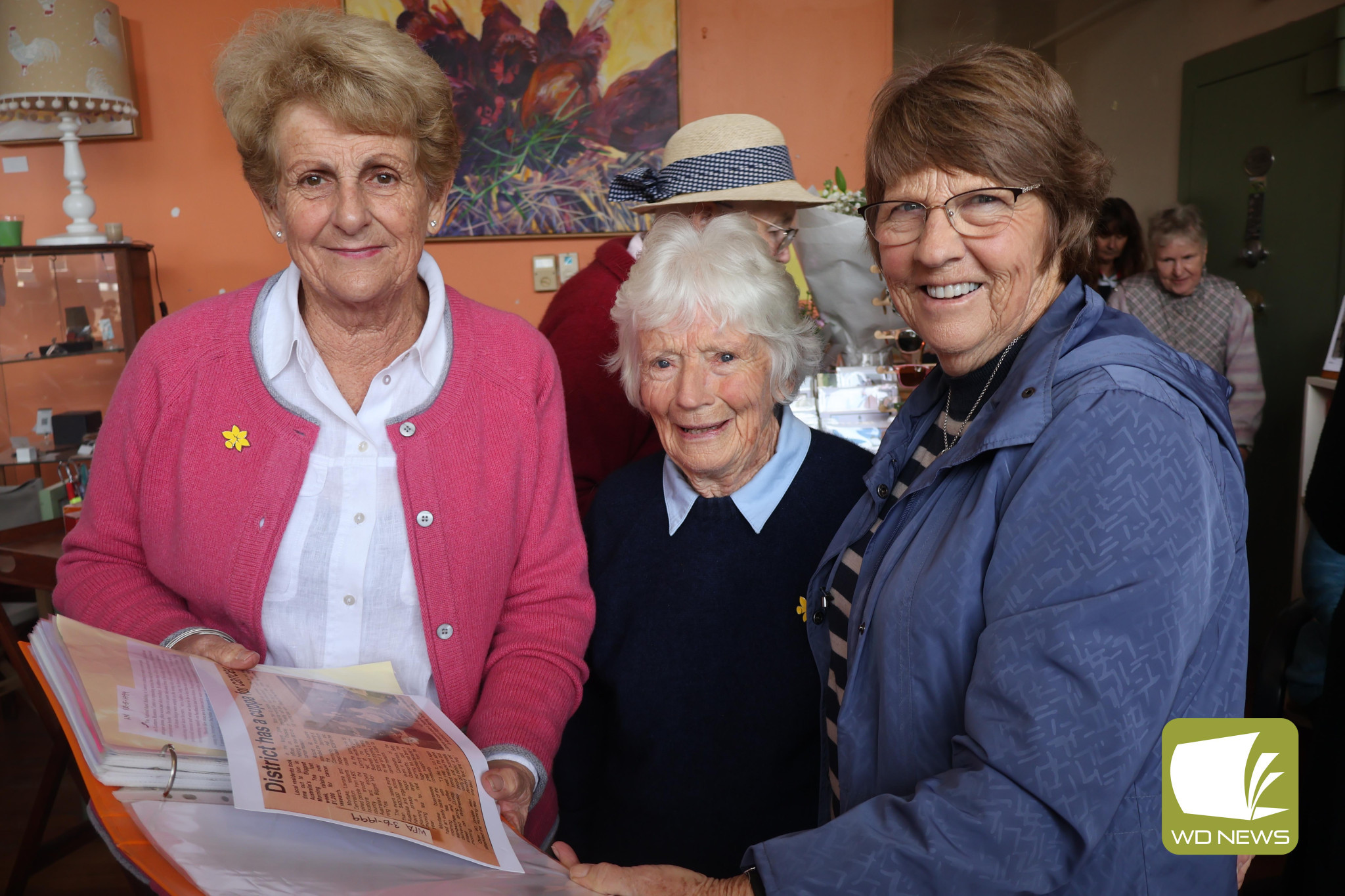 Reminiscing: Sandy Gibson, Shelia Brett and Kathy Bell look back on an article from the first Lismore Biggest Morning Tea in 1999.